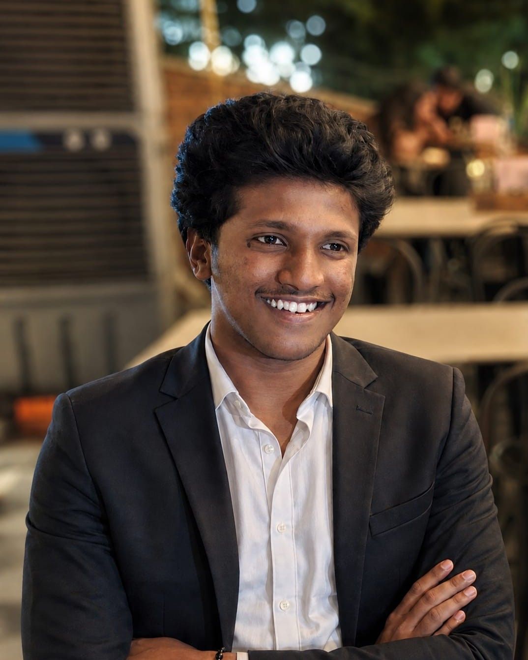 Karthikeya Veeramallu smiling, in a black suit and white shirt